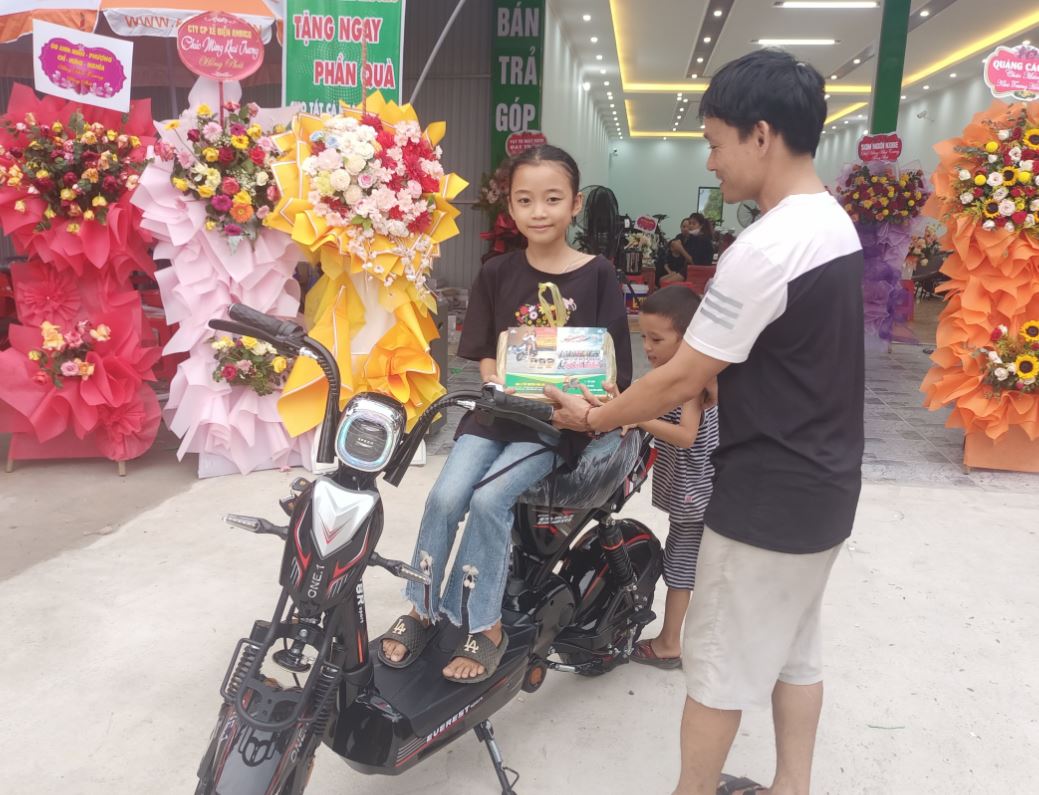 Hình ảnh bé gái ngồi trên xe điện rồi nhận được những phần quà từ sự kiện